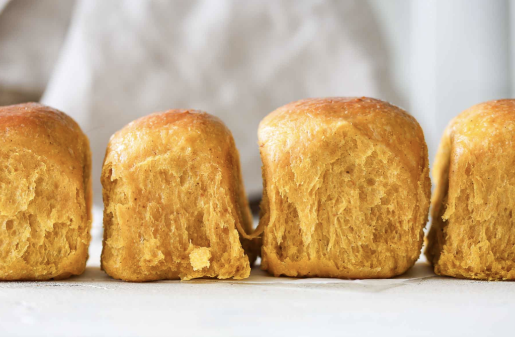 Sourdough starter discard pumpkin rolls in a line, ready to be enjoyed.