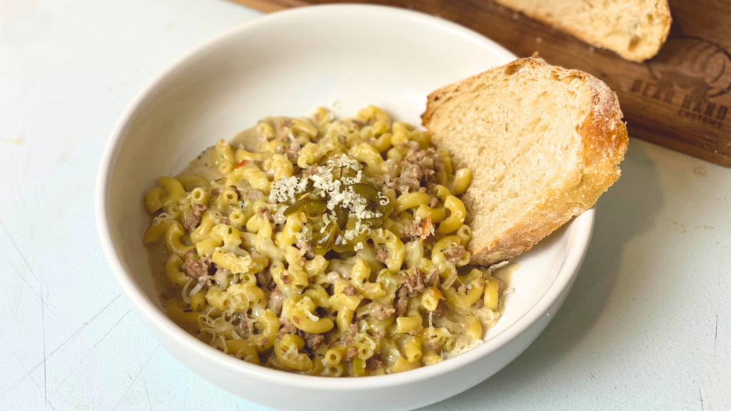 One-Pot Cheeseburger Pasta in a white bowl with a slice of sourdough bread on a white countertop