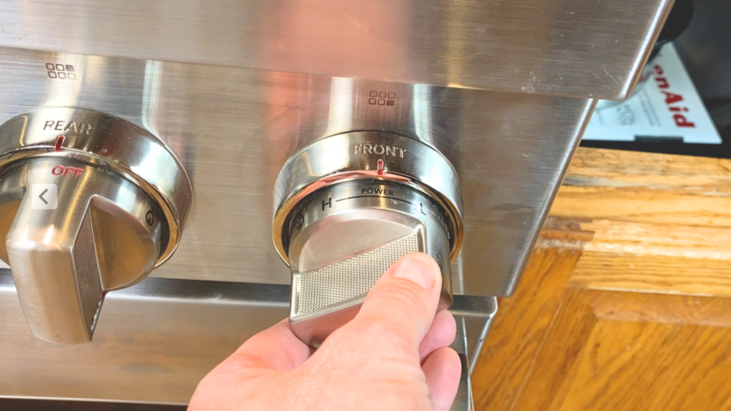 Close up of a woman turning the temperature of a stove burner up the medium-high heat